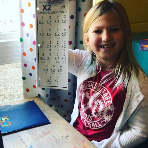 Girl at micro school displays multiplication work.