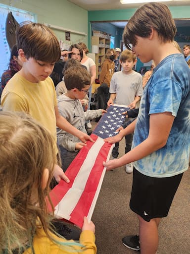 Students fold flag as part of World War 2 theme at project based school.